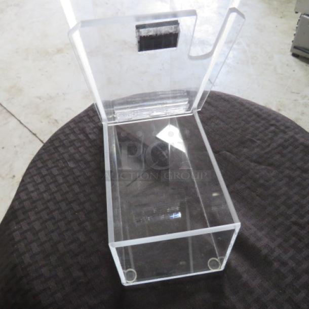Clear acrylic display case, open-top design, excellent condition, suitable for collectibles, two small circular feet.