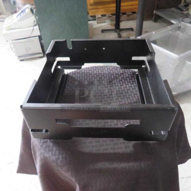Black metal tray or rack, likely for industrial use, shows no visible wear. Features cut-out handles and open frame design.