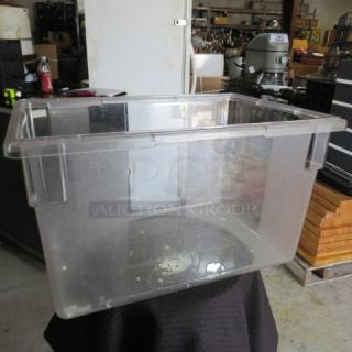 Clear plastic storage bin, large size, with reinforced edges and molded handles. Shows slight wear, suitable for industrial use.