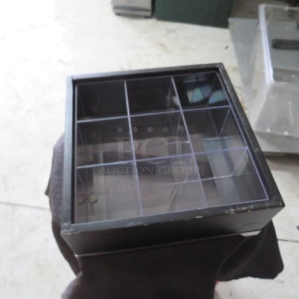 Black wooden display box with nine clear compartments. Transparent lid. In good condition. Ideal for collectibles.