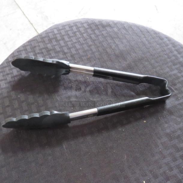 Metal and silicone kitchen tongs on black textured surface, in used condition, with no visible tags or markings.