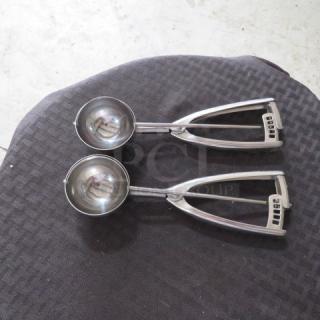 Two stainless steel ice cream scoops with lever mechanism, polished finish, and ergonomic handles, in good condition.