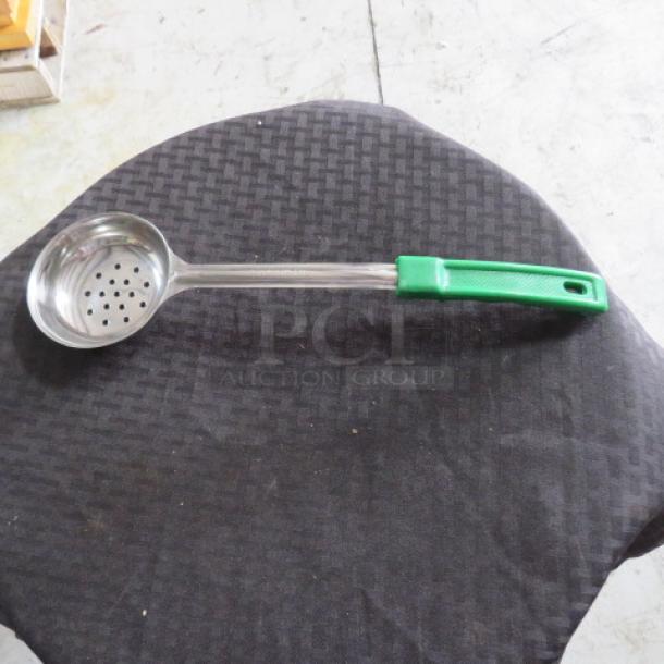 Stainless steel ladle with perforated bowl and green plastic handle, in good condition, ideal for straining liquids.