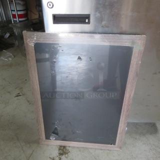 Wood-framed blackboard, medium size, minor surface scratches, protective film partially removed, leaning against a metal object.