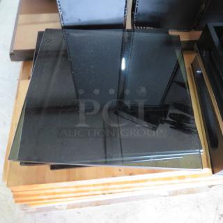 Black glass panel, square, polished finish, stacked in storage. Suitable for furniture or construction use. No visible markings.