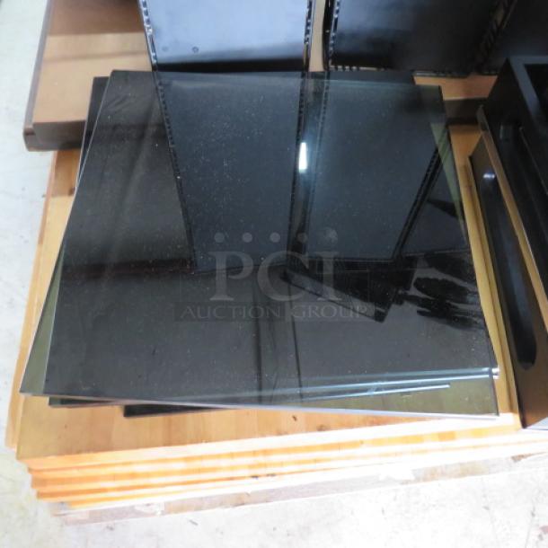 Black glass panel, square shape, reflective surface, appears in good condition, possibly for industrial or decorative use, stacked on a wooden pallet.
