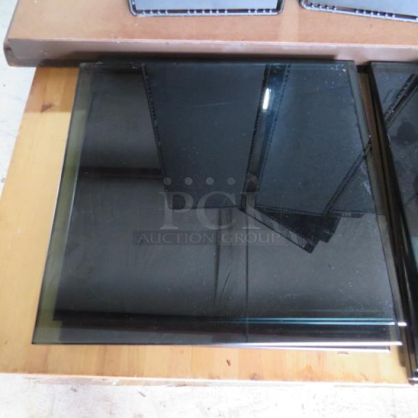 Stack of black tempered glass panels, glossy finish, squared shape, lightly reflective surface, excellent condition.