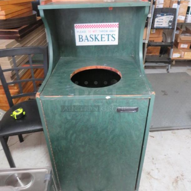 Green wooden basket bin with round opening, "Please Do Not Throw Away Baskets" sign, some wear visible on surface.