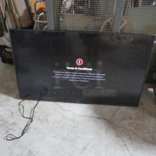 Flat-screen TV displaying terms and conditions message. Used condition, visible power cable, placed on marble floor.