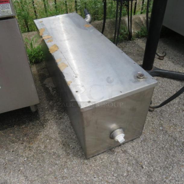 Stainless steel rectangular tank with a spout and valve, showing signs of wear and rust along the edges.
