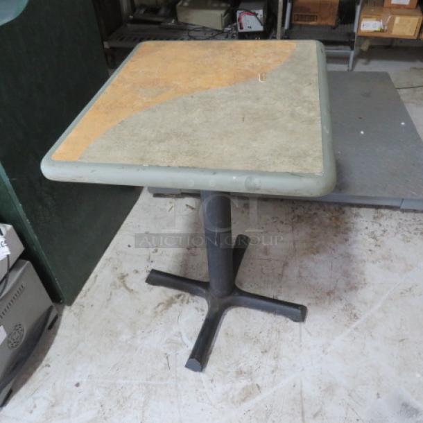 Square pedestal table with a stone-like top featuring a two-tone design. Metal base, shows wear, sturdy construction.