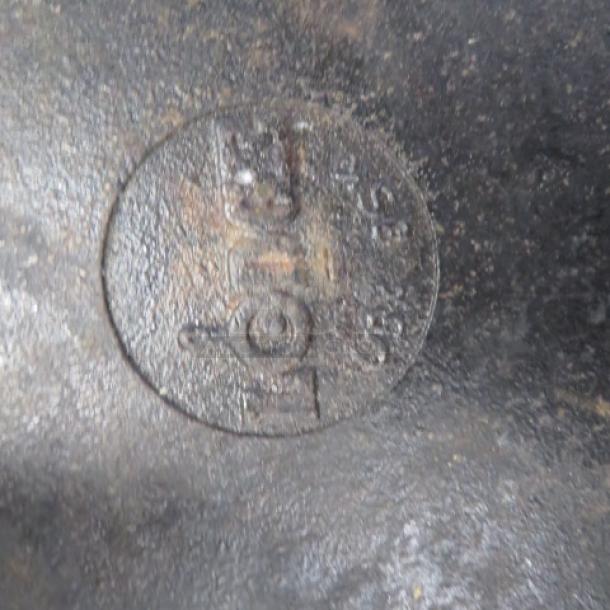 Vintage cast iron skillet base with visible circular marking "7". Worn, seasoned patina indicating age and use.