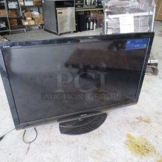 Sharp Aquos flat-screen TV, black, on stand, showing "INPUT5 HDMI" on screen, used condition, power cable visible.