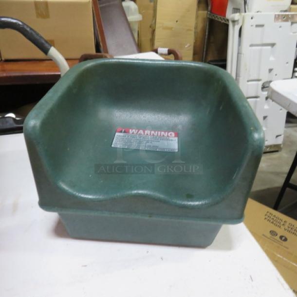 Green molded plastic seat with "Warning" label, minor wear visible. Ideal for industrial or commercial use.