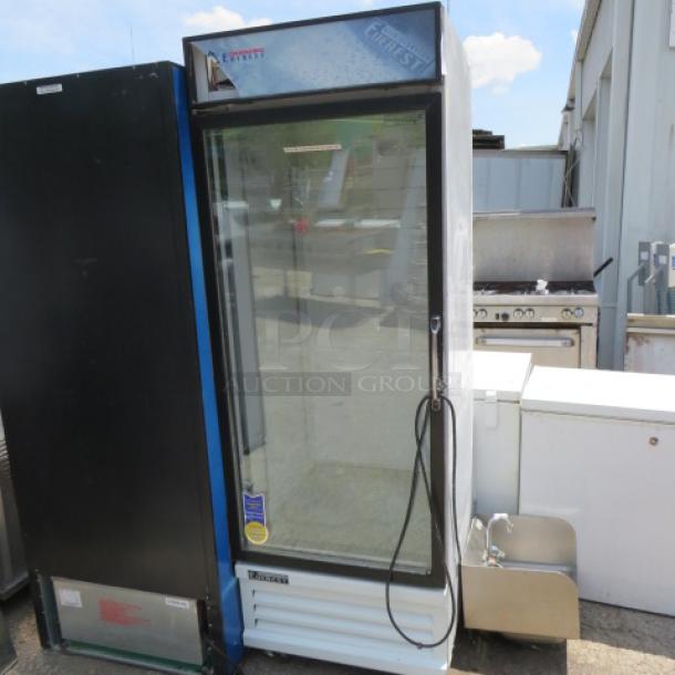 Glass door commercial refrigerator. Everest brand, model R1. Visible wear, stickers displaying branding and model. Single door unit.