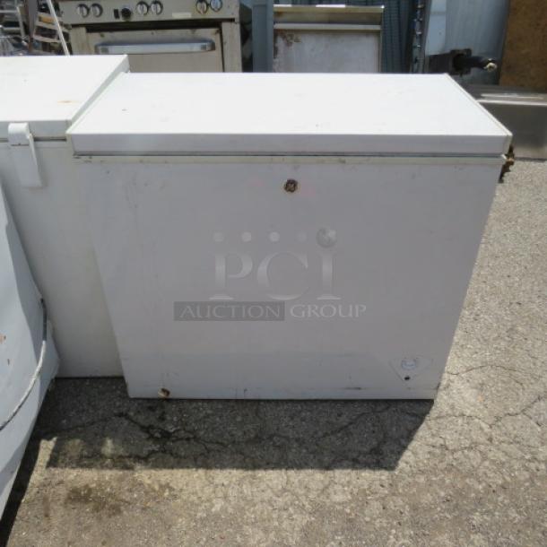 White chest freezer with a top-opening lid, minor rust, and wear. Suitable for commercial use. No visible brand.