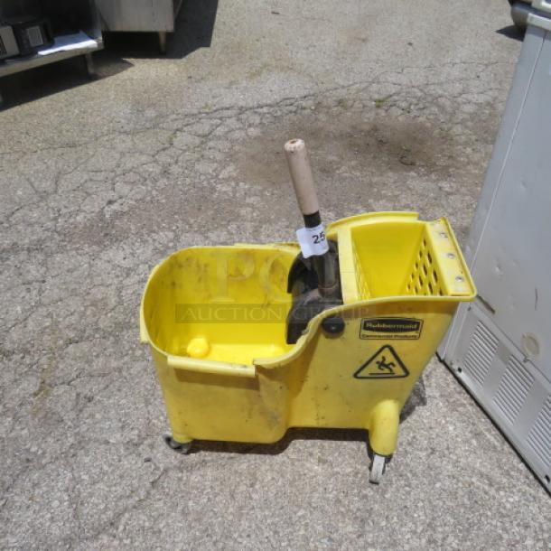 Yellow Rubbermaid mop bucket with wringer on wheels, used condition. Features caution sign and label with model info.