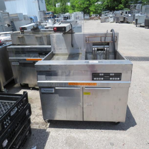 Commercial Frymaster deep fryer with dual baskets, stainless steel finish, digital controls, shown outdoors. Good condition.
