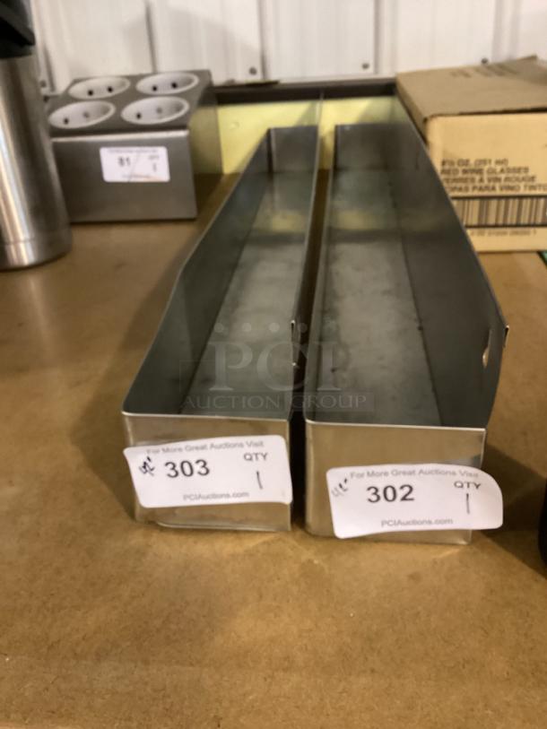 Two rectangular stainless steel trays with auction labels 302 and 303, quantity 1 each, on a wooden surface.