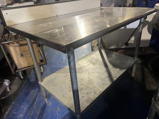 Stainless steel prep table, 48"x24"x39.5". Features a lower shelf and backsplash. Used condition with some surface scratches.