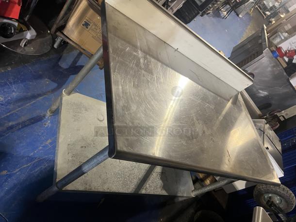Stainless steel prep table, 48x24x39-1/2 inches, scratched surface, sturdy metal legs, lower shelf, suitable for kitchen use.