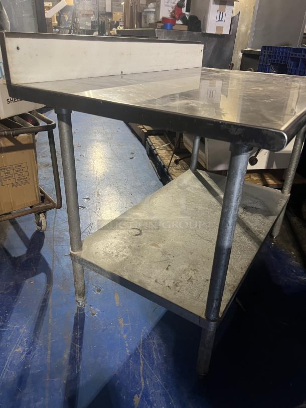 Stainless steel prep table, 48"x24"x39.5", durable metal frame, two-tier, good condition, ideal for kitchen use.