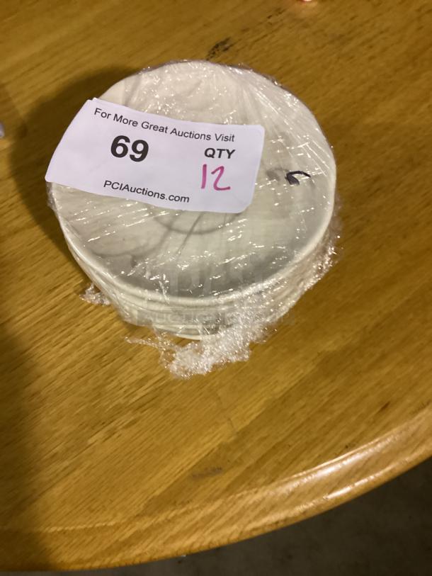12 white dessert plates, 5-1/2 inches, wrapped in plastic. Auction tag shows lot 69, quantity 12.