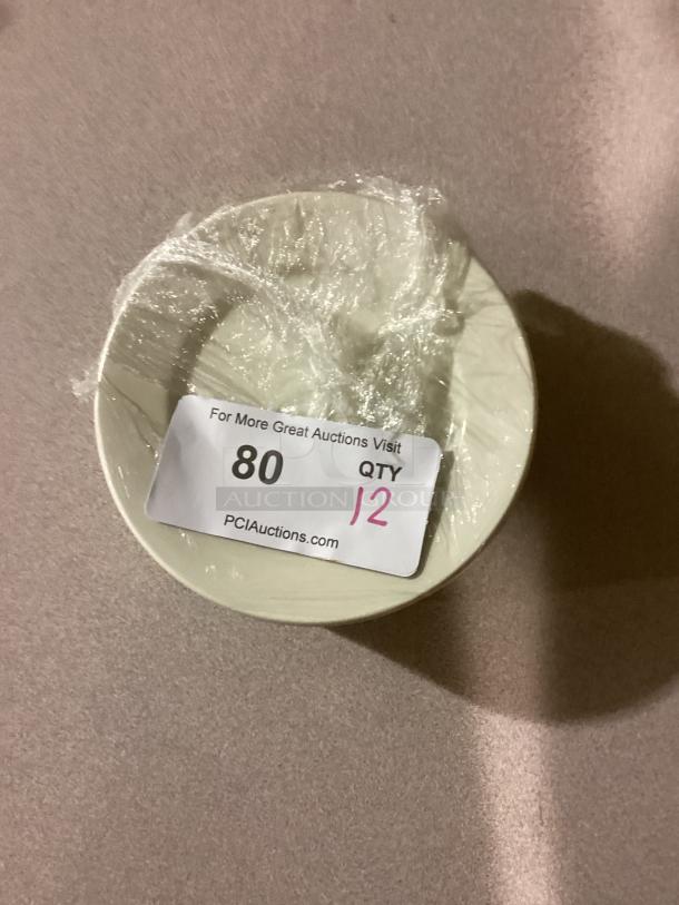 Set of 12 medium desert plates, 6-1/2 inches, wrapped in plastic. Auction label showing quantity and auction site details.