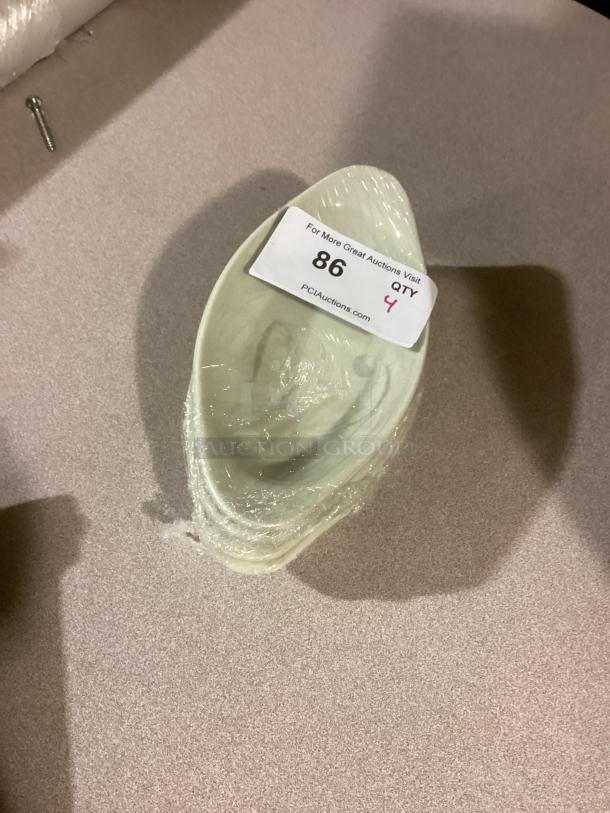 Large serving bowl, oval shape, green hue, 9-5/8 inches. Quantity: 4. Wrapped in plastic. Auction label indicates item 86, Qty 4.