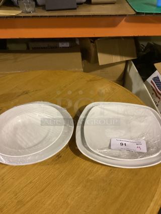 Set of four white serving plates in varying sizes: 9-1/2", 11-1/4", 9-3/4", 11-1/2". Wrapped in plastic, excellent condition.