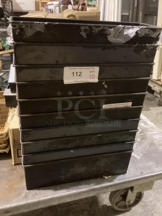 Stack of 10 black 16-1/8" bread pans with visible wear, labeled "112 QTY 10," on a metal cart in an auction setting.