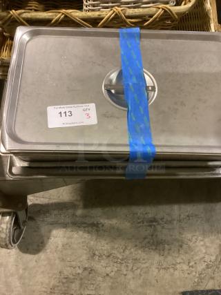 Three stainless steel food pans, 16-1/8 size, stacked, with auction lot tag 113 and quantity 3. Some surface wear visible.