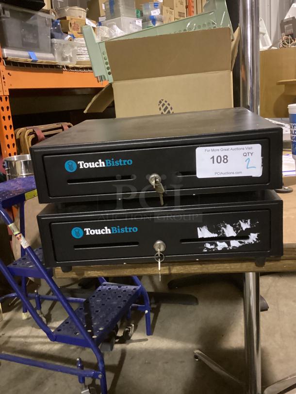 Two TouchBistro cash registers, black, each with a key. Visible label reads "Qty: 2." Some wear on the lower register.