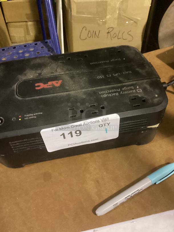 APC UPS ES 350 battery backup and surge protection unit, slightly dusty, item tag "119 QTY 1" visible on top.