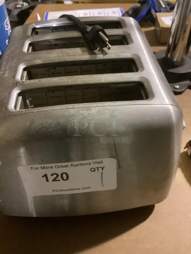 Stainless steel four-slot toaster with power cord, showing some wear. Auction label reads "QTY 1, 120, PCIAuctions.com".