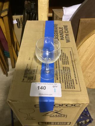 Small wine glass, 5-3/8" tall, on cardboard box labeled "GLASSWARE HANDLE WITH CARE." Auction tag "140, QTY 1" visible.