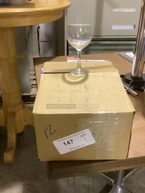 Red wine glass on cardboard box, 8-1/2 inches tall. Auction tag shows quantity 1, item number 147.