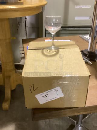 Red wine glass on cardboard box, 8-1/2 inches tall. Auction tag shows quantity 1, item number 147.