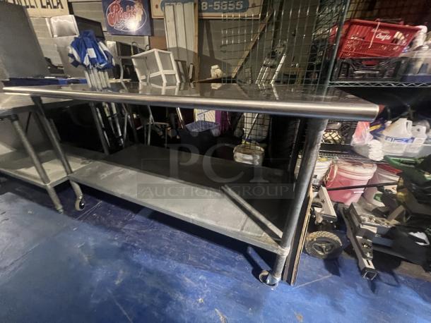 Stainless steel table with wheels, 72x30x39 inches. Features lower shelf, polished top, used condition.