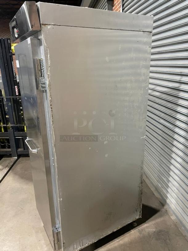 Commercial stainless steel refrigerator, upright model, used condition with visible wear, heavy-duty handle, visible control panel.