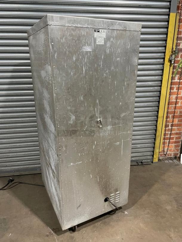 Commercial stainless steel warming cabinet, pre-owned, vertical design, visible scuffs, rolling casters, metal latch.