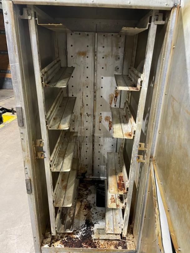 Metal storage cabinet with multiple shelves, showing significant rust and wear. Hinged door. Ideal for industrial use.