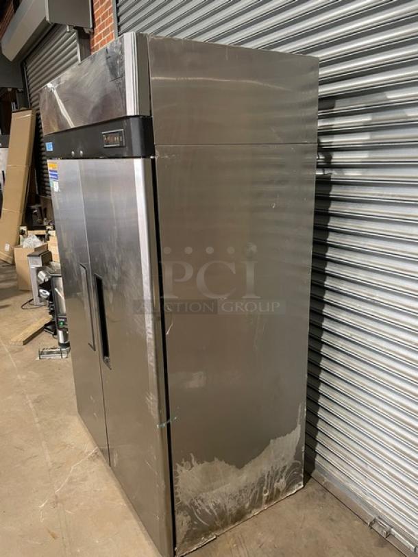 Commercial stainless steel refrigerator with dual doors and top control panel. Shows signs of use, some surface scratches.