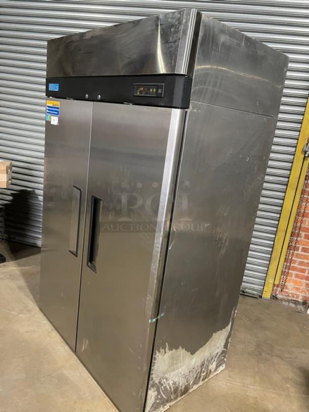Commercial stainless steel refrigerator, dual doors, some exterior wear, digital temperature display, ideal for restaurant use.