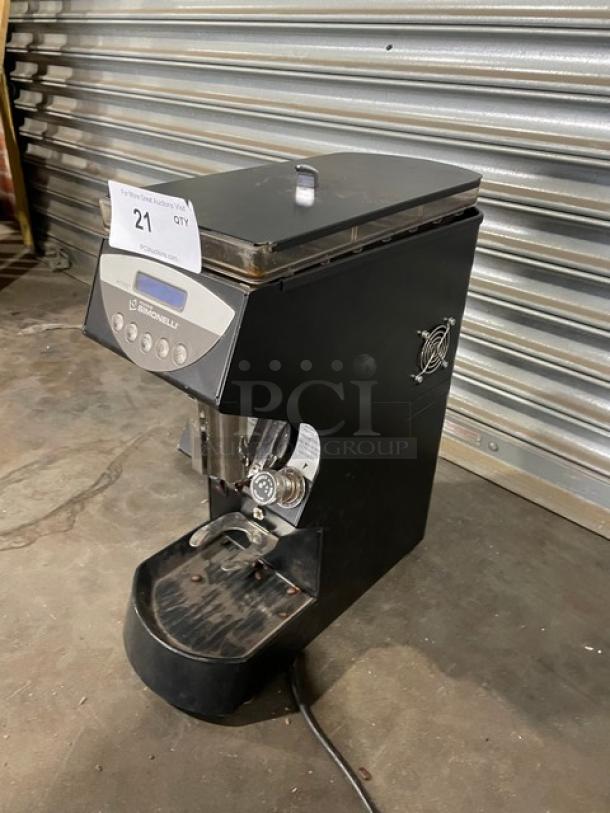 Black Nuova Simonelli espresso grinder, used condition, visible wear on tray. Label indicates item #21 for auction.