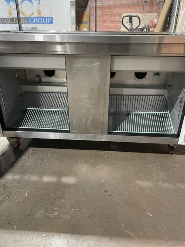 Commercial stainless steel refrigeration unit, dual open compartments, on casters. Used condition, suitable for a kitchen.