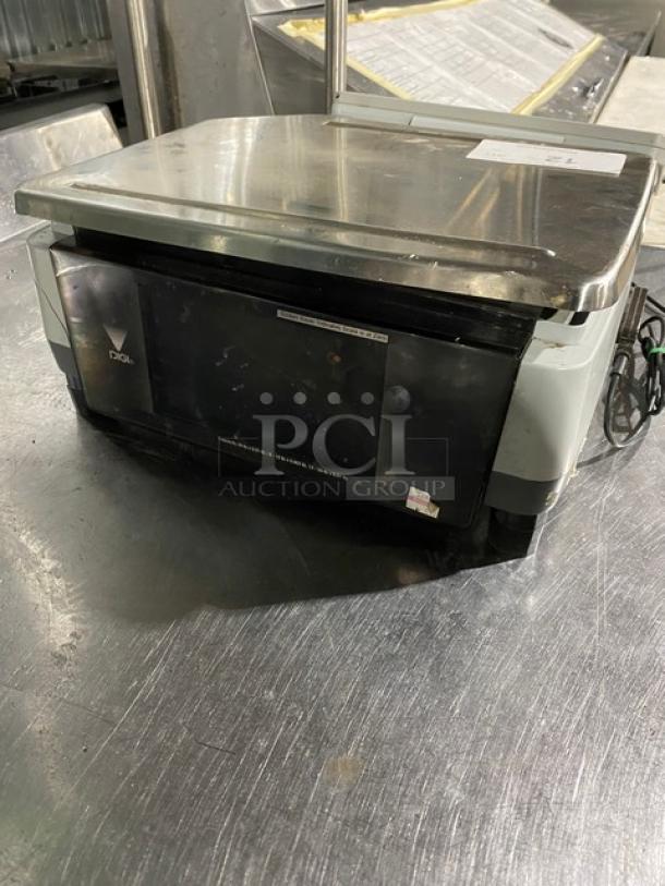 Commercial digital scale with stainless steel top and black digital display, shows moderate wear. Brand visible: Digi.