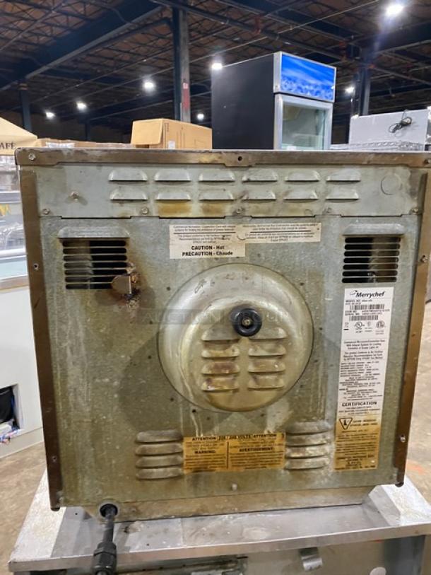 Industrial microwave oven, Merrychef brand, showing wear and rust. Warning labels detail operation and safety precautions.