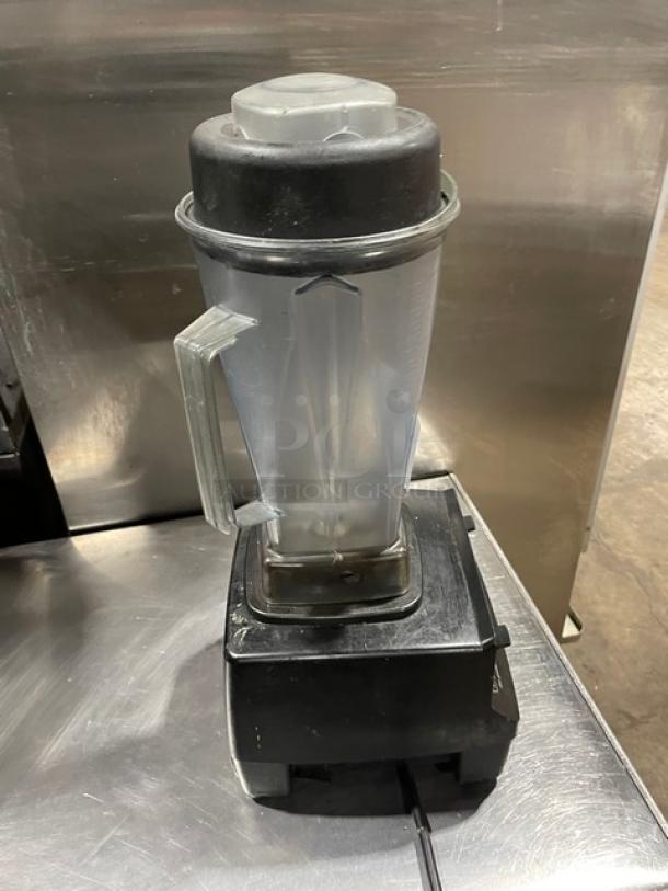 Commercial blender in used condition with clear plastic pitcher and black base on stainless steel surface. No visible labels.