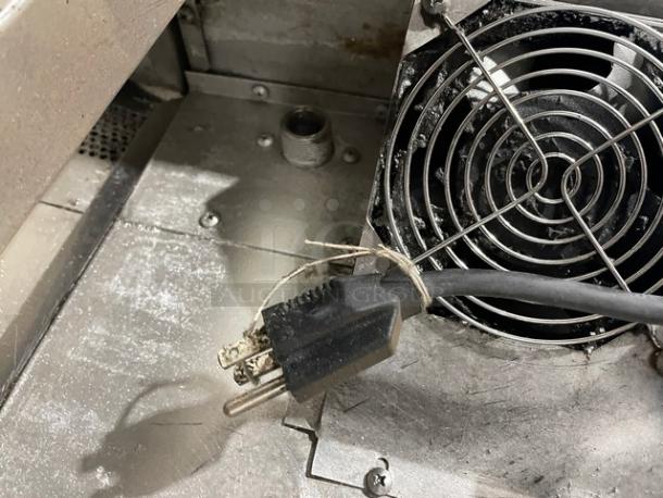 Industrial equipment fan and power cord in used condition, visible dust and wear, indicative of previous use.